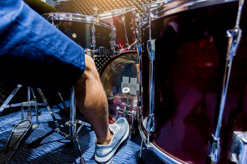 man put white sport shoes and playing the drum set and bass drum with foot in music room