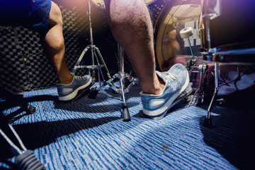 man put white sport shoes and playing the drum set and bass drum with foot in music room - obrazy, fototapety, plakaty