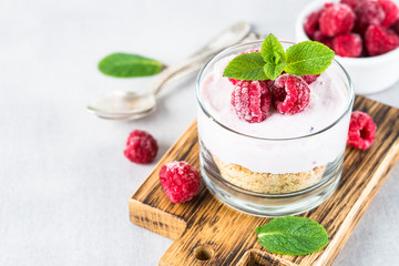 No baked cheesecake with raspberry in glass jar.