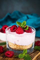 No baked cheesecake with raspberry in glass jar.
