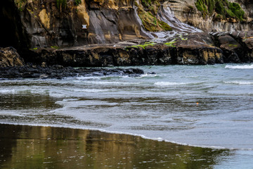 Rocky shoreline is waves swept, Murawai Beach, Auckland, New Zealand