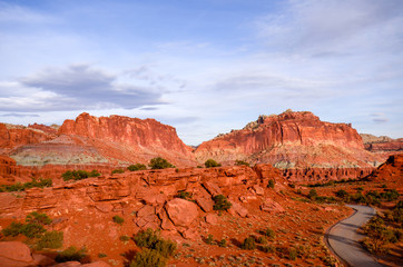 Sunset during golden hour in Southern Utah, sun warming red sandstone, cliffs, mountains, and mesa