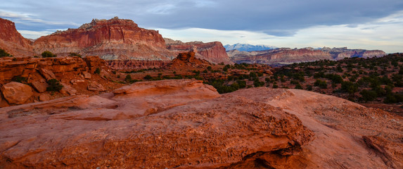 Sunset during golden hour in Southern Utah, sun warming red sandstone, cliffs, mountains, and mesa