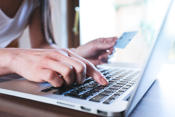 Frau hält Kreditkarte und kauft Online am Laptop ein