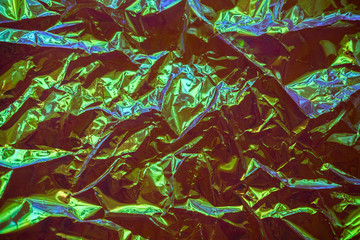 Holographic real texture in iridescent blue green colors with folds and irregularities. Holographic color wrinkled foil. Crumpled Abstract texture background