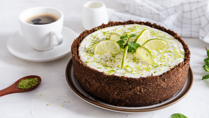 Homemade cheesecake with lime and mint for dessert - healthy organic summer dessert pie cheesecake. Cheese cake with a cup of coffee on white background