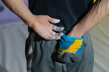 Closeup image of male hands near a climbing wall