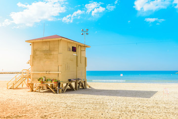 Yellow lifeguard tower at sandyTel Aviv Beach, Israel, against blue horizon. Summer, baywatch, vacation and travel concept. 