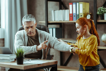 Positive delighted girl distracting her dad from work