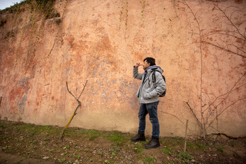Obraz na płótnie Canvas young man tourist with camera against sand wall