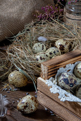 Cute still life with quail eggs. Quail eggs in the nest and on the old wooden table in the barn among vintage items and dried flowers
