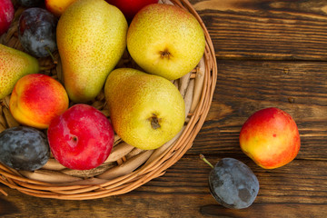 ripe pears and red plums on a wooden table