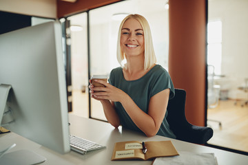 Smiling businesswoman drinking coffee while working in an office