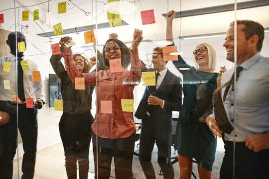 Cheering businesspeople celebrating together after an office bra