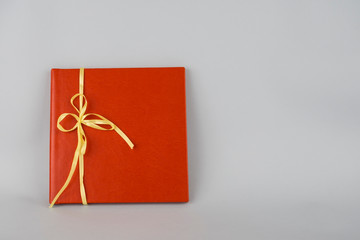 Red book with yellow ribbon. Red gift on gray background