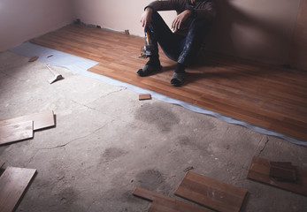 Worker installing new laminate wooden floor.