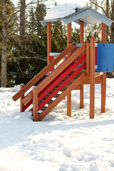 Colorful wooden empty nobody children's playground with a slide for activity childrens play in the winter on the snow