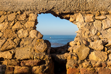 Stone wall with a hole and Atlantic ocean