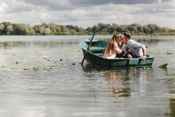 Just relaxing. Beautiful young couple enjoying romantic date while rowing a boat. Loving couple resting on a lake while riding a green boat. romance.