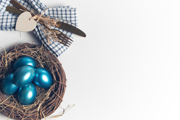 easter eggs blue on background with spoon and fork and dried grass with wood vine and flower