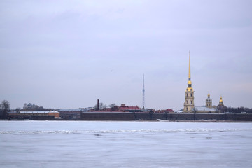 Fototapeta premium Saint Petersburg, Russia - March 17 2019: The view of the Peter and Paul Fortress and frozen Neva river from the embankment on a cloudy day