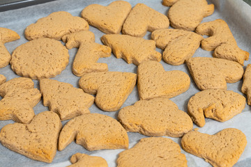 fresh baking cookies of different shapes on a baking sheet close-up