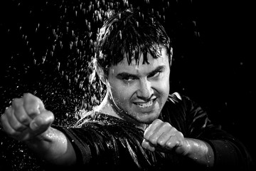A young man wearing a jacket poses in a wushu stance while it rains down on him on March 20, 2009.