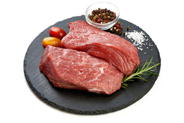 Fresh raw beef steaks on slate shale plate, sliced meat, close-up, isolated on white background