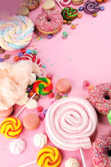 candies with jelly and sugar. colorful array of different childs sweets and treats on pink