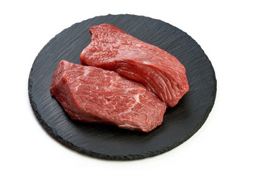 Fresh raw beef steaks on slate shale plate, sliced meat, close-up, isolated on white background