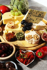 Italian antipasti wine snacks set. Cheese variety, Mediterranean olives, crudo, Prosciutto di Parma, salami and wine in glasses over grunge background.