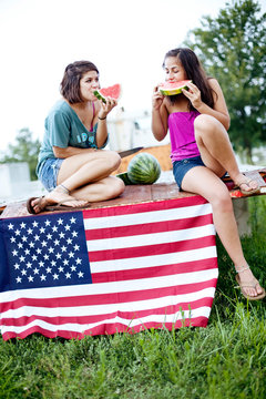 Two sisters eat watermelon on flatbed truck
