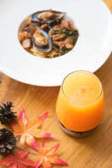 A glasses of orange juice on wooden table with shell spaghetti
