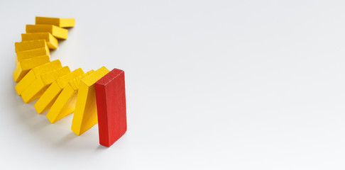 Yellow wooden blocks following red leading one in falling chain