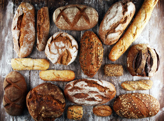 Different kinds of bread and bread rolls on board from above. Kitchen or bakery
