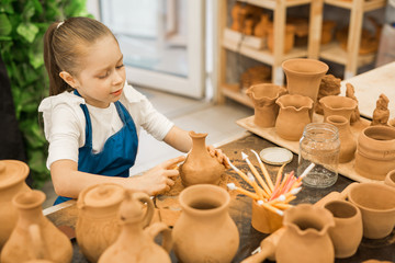 beautiful little girl making a pot of clay in a pottery workshop
