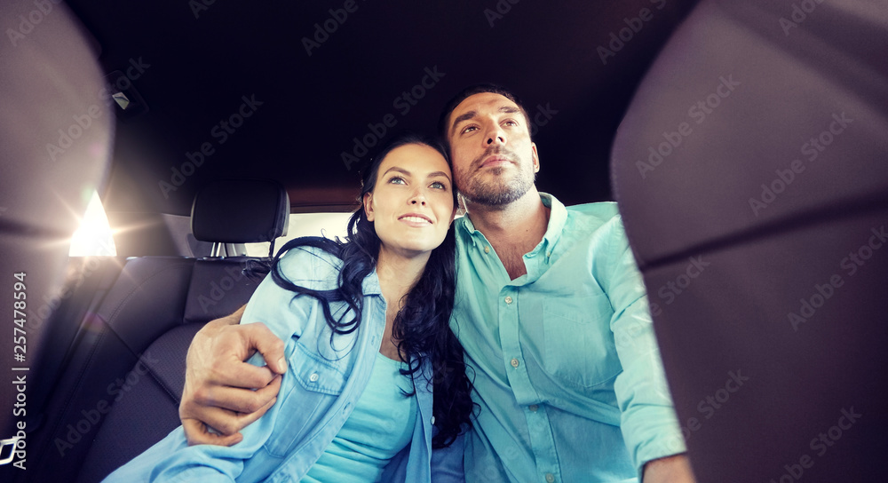 Sticker transport, road trip, travel and people concept - happy man and woman riding on a back seat of taxi car and hugging