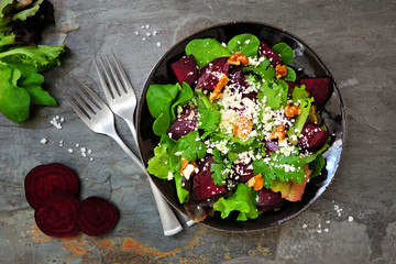 Healthy salad with beets, mixed greens, carrots and feta cheese. Top view table scene against a...