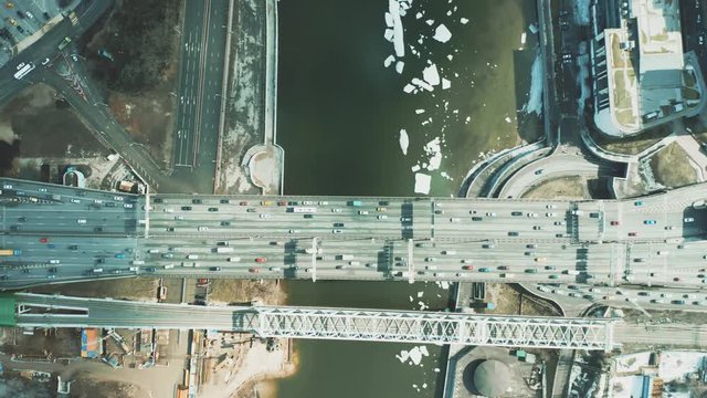 Aerial top down view of car and railway bridges above icy river