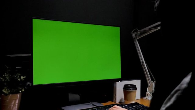 Zoom in shot Asian girl sitting at her desk with Chroma key green screen background of computer monitor, Working at night