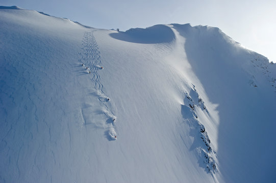 A group of heliskiers at CMH Cariboos decends a steep face.