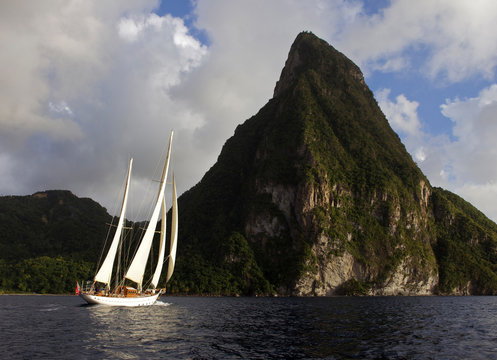 Classic sailing yacht "Sincerity", a 1928 Baglietto designed ketch, cruises past the dramatic Pitons along the coast of St. Lucia in the Caribbean.