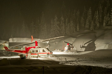 Bell 212 and 206 helicopters used for heli-skiing parked in heavy snowfall in Canada.