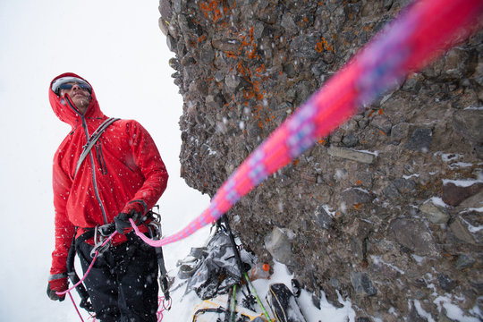 Zach Fletcher belyaing another climber while ice climbing in wintery conditions at Red Cliffs in Kirkwood, California.