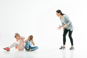 Obraz premium Angry mother scolding her son and daughter at home. Studio shot of emotional family. Human emotions, childhood, problems, conflict, domestic life, relationship concept