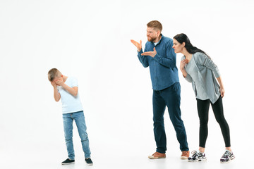 Angry parents scolding their son at home. Studio shot of emotional family. Human emotions, childhood, problems, conflict, domestic life, relationship concept
