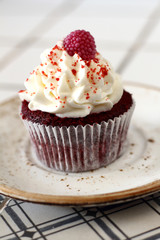 Tasty red velvet delicious sponge cupcake with white butter cream frosting and  raspberrie on plate. Candy bar for celebrating partys and birthdays