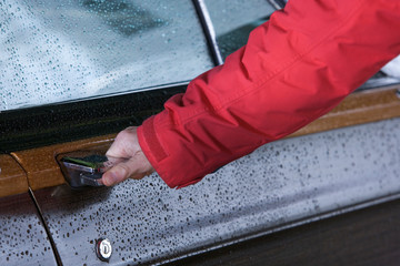 A hand opening a car door.