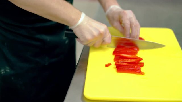 CU: Cook very quickly cuts fresh Bulgarian red pepper with a knife.
