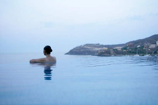 A woman in the main pool overlooking the Pacific Ocean at La Casa que Canta luxury resort in Zihuatanejo, Mexico.  (releasecode: CM_MR1028, CM_MR1032)
